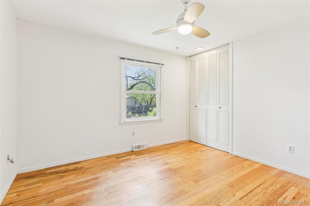unfurnished bedroom with baseboards, visible vents, hardwood / wood-style flooring, and a closet