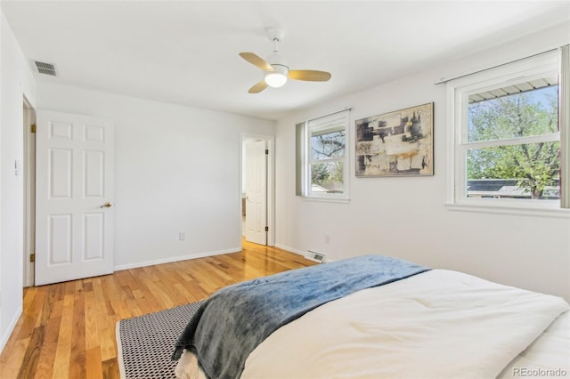 bedroom featuring baseboards, ceiling fan, light wood finished floors, and visible vents