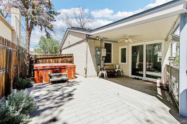 deck with a fenced backyard, ceiling fan, and a hot tub