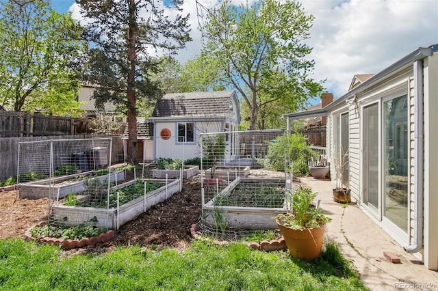 view of yard with a storage unit, fence, an outbuilding, and a vegetable garden