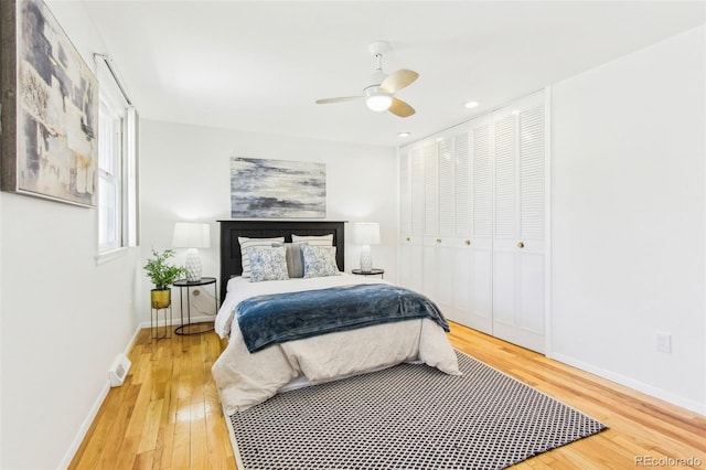 bedroom with baseboards, a ceiling fan, wood finished floors, and visible vents