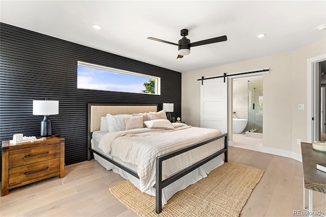 4572 N Raleigh St, Denver, CO 80212 - bedroom featuring an accent wall, a barn door, recessed lighting, light wood-type flooring, and connected bathroom