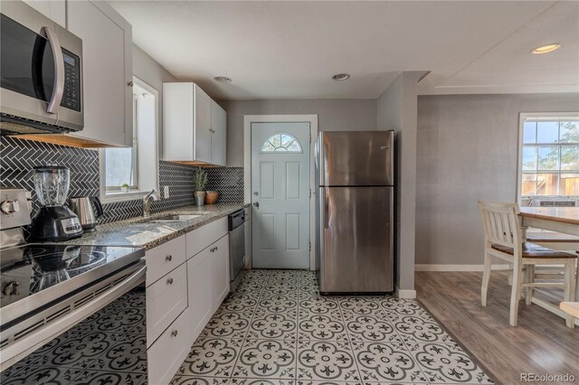 kitchen with white cabinets, sink, light stone countertops, tasteful backsplash, and stainless steel appliances