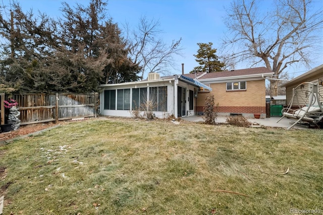 back of house with a sunroom, a patio area, and a lawn