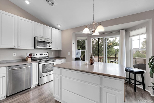 4912 S Fultondale Way, Aurora, CO 80016 - kitchen with stainless steel appliances, a chandelier, wood finished floors, white cabinets, and vaulted ceiling