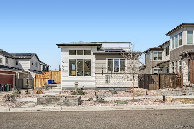 view of front of property featuring solar panels and fence