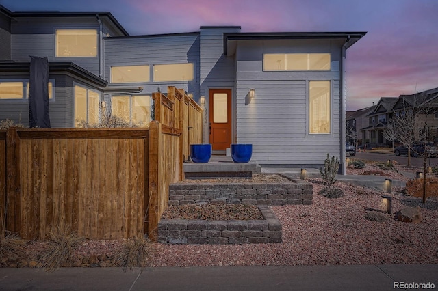 back of house at dusk featuring fence