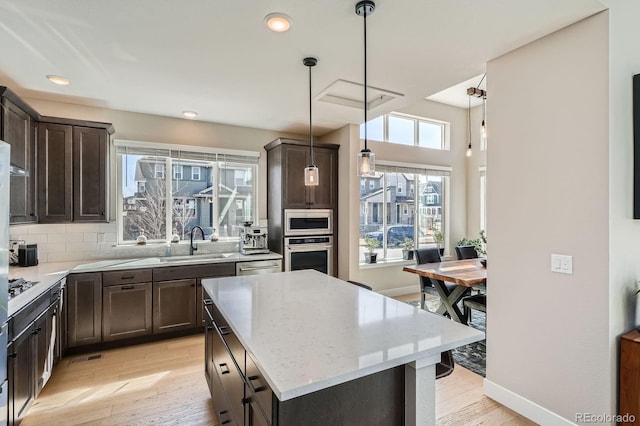 kitchen featuring dark brown cabinetry, light wood-style flooring, stainless steel appliances, and a sink