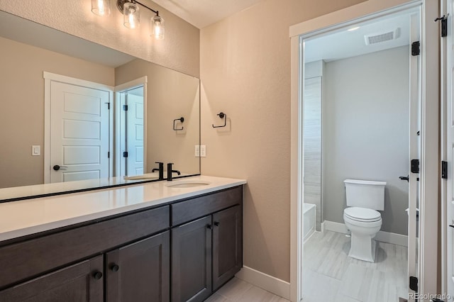 bathroom featuring visible vents, toilet, a washtub, baseboards, and vanity