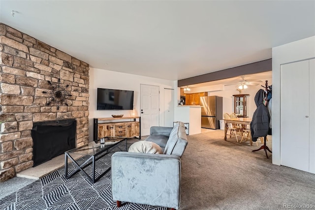 living room featuring carpet flooring, ceiling fan, and a fireplace