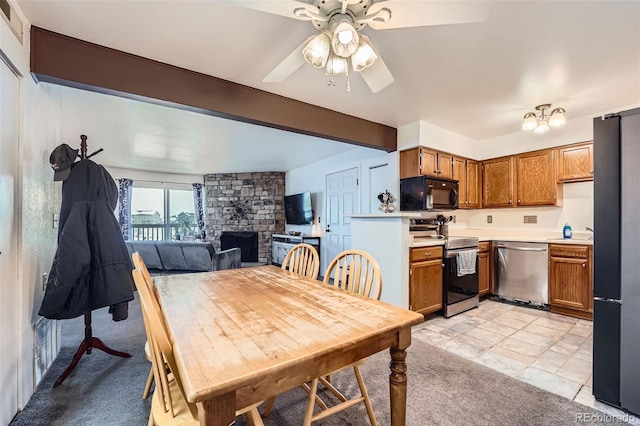 tiled dining area featuring a stone fireplace and ceiling fan