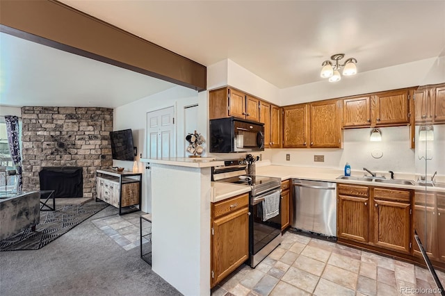 kitchen with stainless steel appliances, sink, kitchen peninsula, a fireplace, and light colored carpet