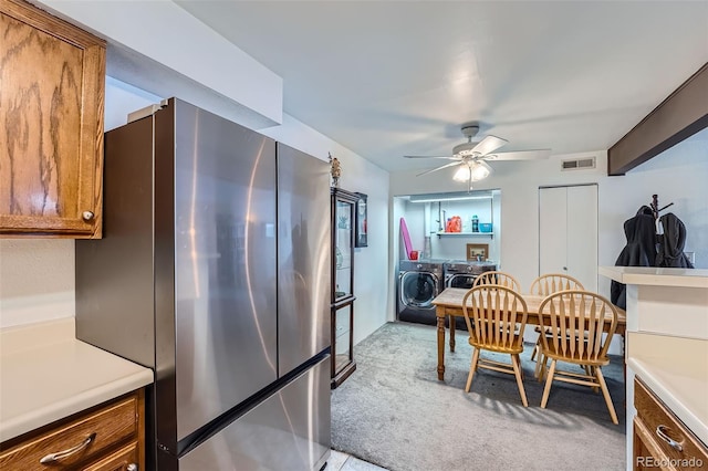 dining area with independent washer and dryer, light colored carpet, and ceiling fan