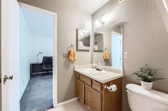 bathroom with toilet, vanity, and tile patterned floors