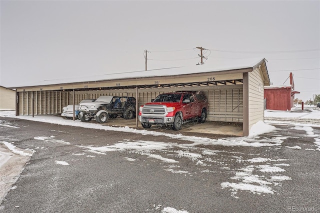 snow covered parking featuring a carport