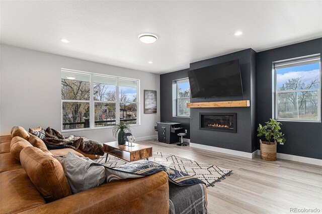 living room with baseboards, a large fireplace, light wood-style floors, and a healthy amount of sunlight