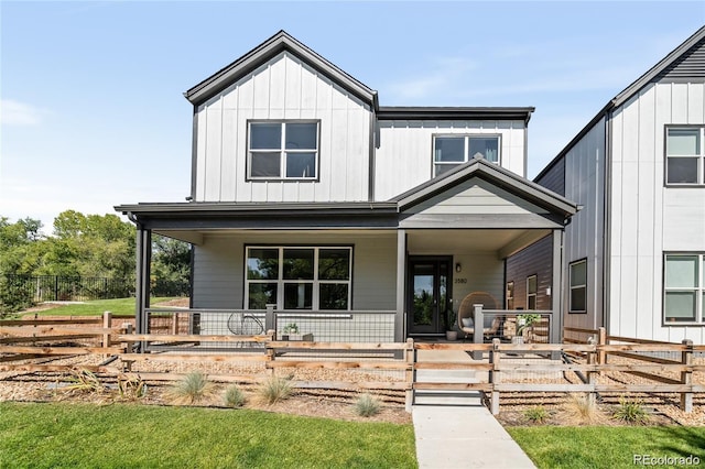 modern farmhouse with a porch, fence, and board and batten siding