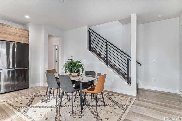 dining space with recessed lighting, light wood-type flooring, baseboards, and stairway