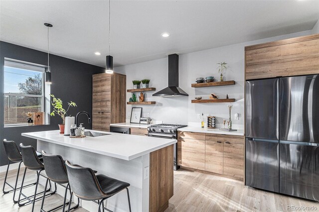 kitchen with open shelves, a sink, wall chimney exhaust hood, stainless steel gas range oven, and freestanding refrigerator