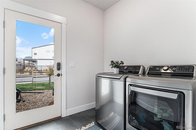 laundry area featuring washing machine and clothes dryer, dark tile patterned flooring, laundry area, and baseboards