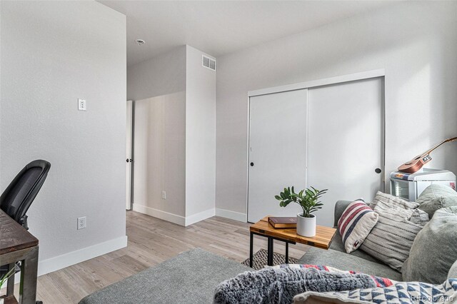 living room with wood finished floors, visible vents, and baseboards