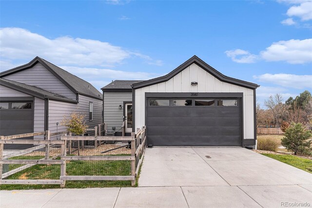 modern inspired farmhouse featuring board and batten siding, an attached garage, driveway, and fence