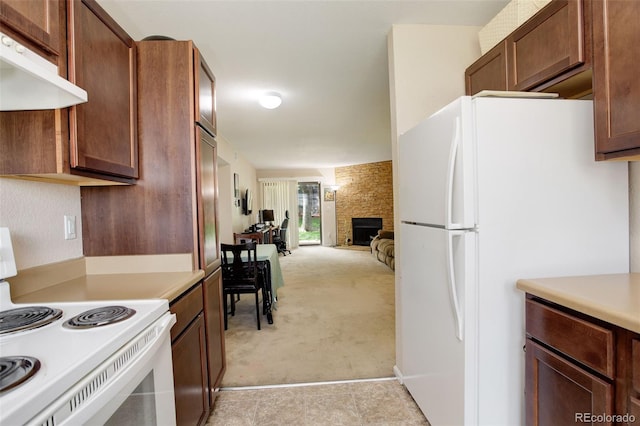 3518 S Depew St Unit 102, Lakewood, CO 80235 - kitchen featuring white appliances, light colored carpet, under cabinet range hood, light countertops, and a stone fireplace