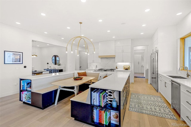 4520 W Moncrieff Pl, Denver, CO 80212 - kitchen with stainless steel appliances, light wood finished floors, white cabinets, an island with sink, and modern cabinets