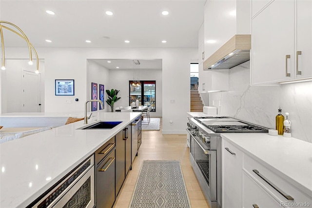 4520 W Moncrieff Pl, Denver, CO 80212 - kitchen with stainless steel stove, premium range hood, white cabinets, light countertops, and recessed lighting