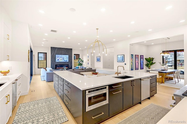 4520 W Moncrieff Pl, Denver, CO 80212 - kitchen featuring stainless steel appliances, white cabinets, a spacious island, light countertops, and light wood-type flooring