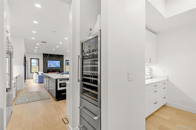 4520 W Moncrieff Pl, Denver, CO 80212 - kitchen featuring white cabinetry, modern cabinets, beverage cooler, light wood-type flooring, and light countertops