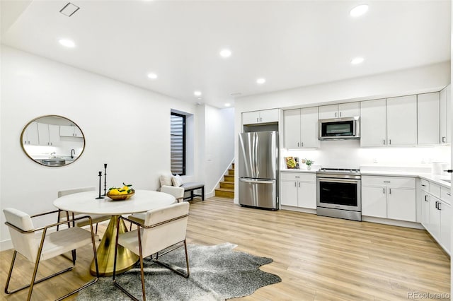 4520 W Moncrieff Pl, Denver, CO 80212 - kitchen featuring stainless steel appliances, light wood-style flooring, light countertops, white cabinetry, and recessed lighting