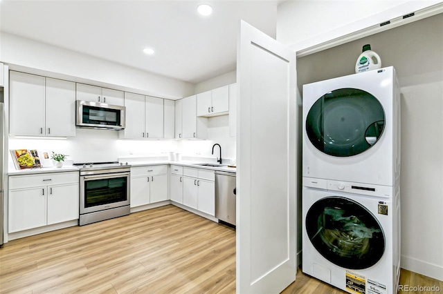 4520 W Moncrieff Pl, Denver, CO 80212 - washroom featuring stacked washer and clothes dryer, light wood-style flooring, and recessed lighting