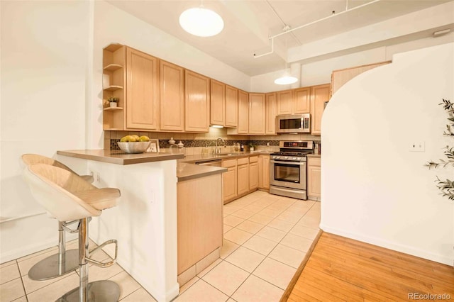 1140 Columbine St Unit 106, Denver, CO 80206 - kitchen with stainless steel appliances, a sink, light brown cabinets, and a peninsula