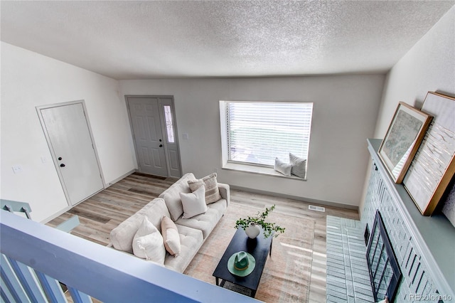 living area with a textured ceiling, baseboards, and wood finished floors