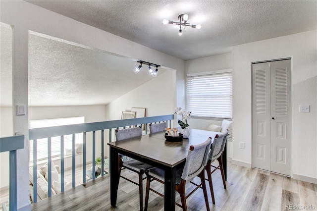 dining area featuring a wealth of natural light, light wood-style floors, a textured ceiling, and baseboards