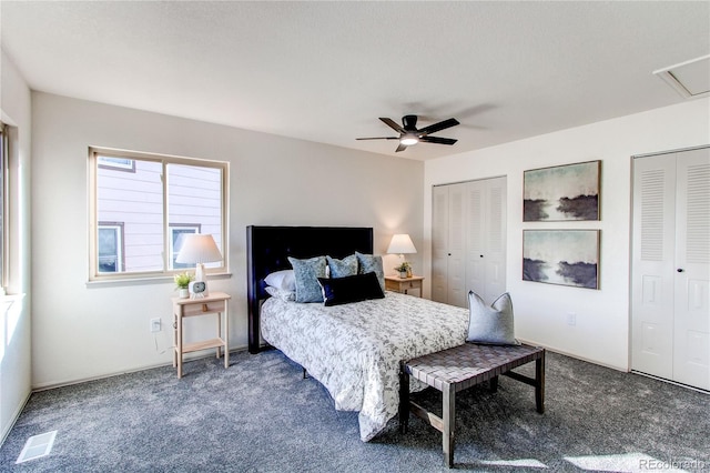carpeted bedroom with two closets, ceiling fan, and visible vents