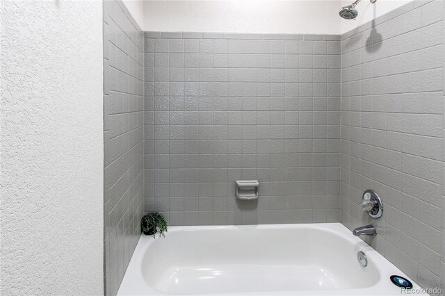full bath with shower / bath combination and a textured wall