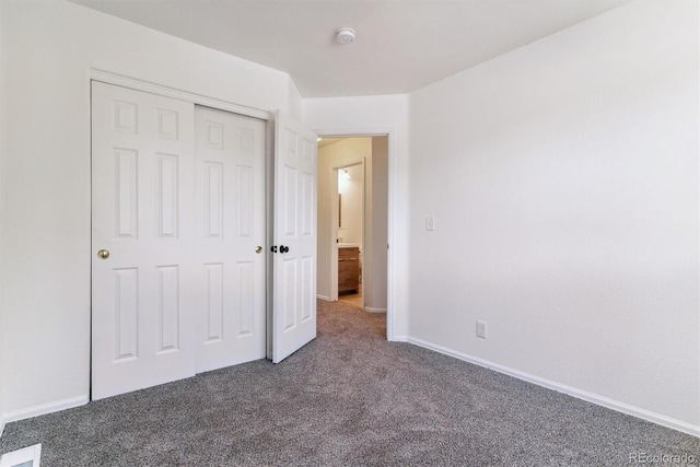 unfurnished bedroom with dark carpet and a closet