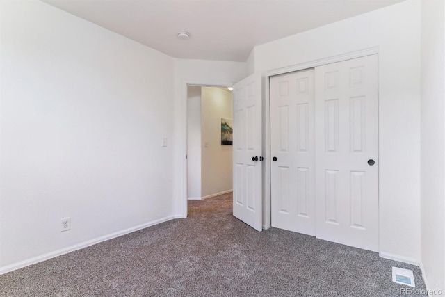 unfurnished bedroom featuring dark colored carpet and a closet