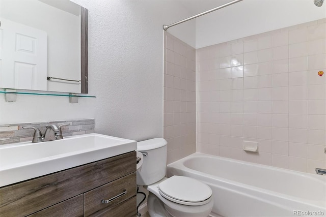 full bathroom featuring tiled shower / bath, vanity, and toilet