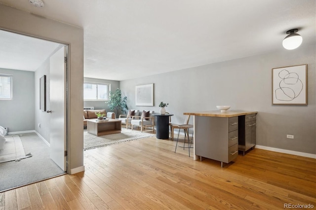 living area with light wood-style flooring, plenty of natural light, and baseboards
