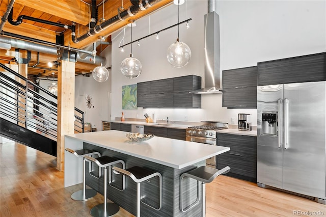 kitchen featuring range hood, a center island, light hardwood / wood-style flooring, high end appliances, and decorative light fixtures