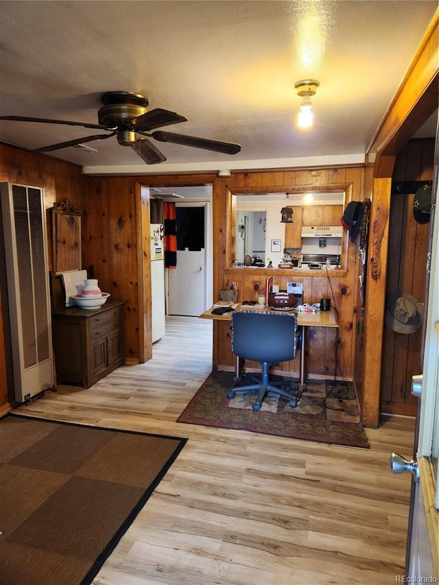 interior space with wooden walls, ceiling fan, and light hardwood / wood-style flooring