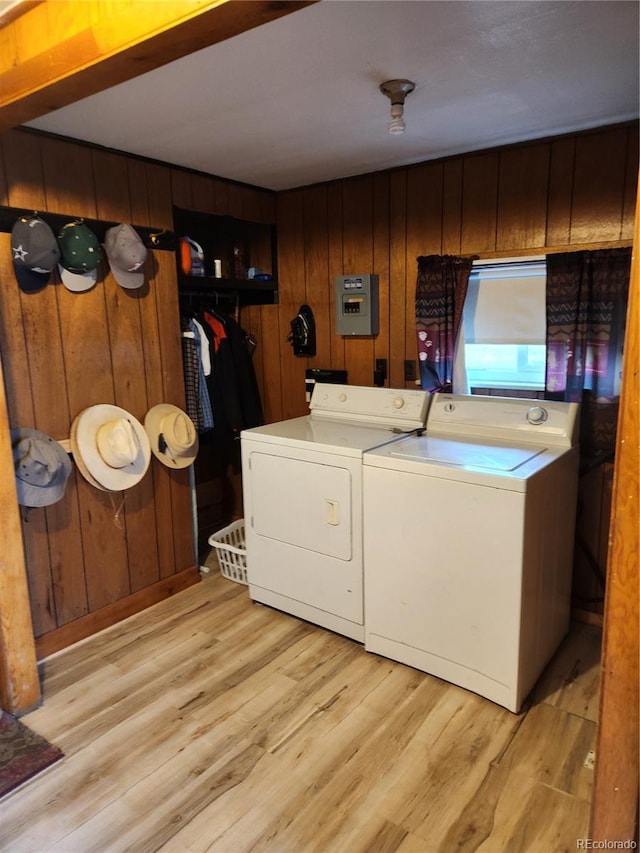 laundry room featuring separate washer and dryer, wooden walls, and light hardwood / wood-style floors