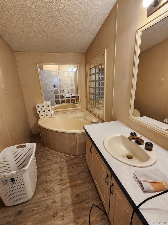 bathroom featuring a bath, a textured ceiling, hardwood / wood-style flooring, and vanity