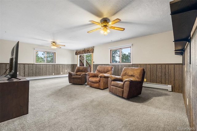11608 Apache Trl, Conifer, CO 80433 - living area featuring a baseboard radiator, wainscoting, a ceiling fan, wooden walls, and carpet flooring