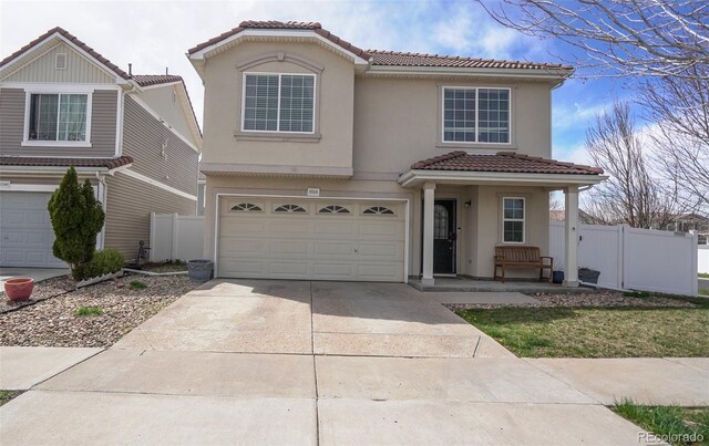 view of front facade featuring stucco siding, driveway, a garage, a tiled roof, and fence