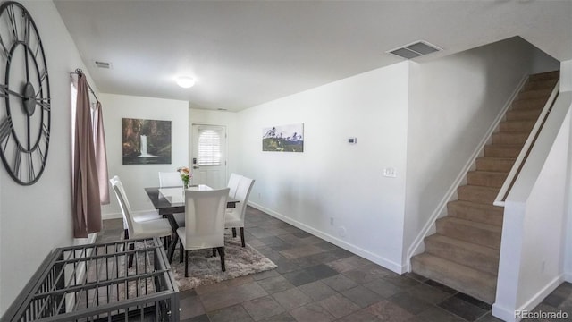 dining room featuring stone finish flooring, stairway, visible vents, and baseboards