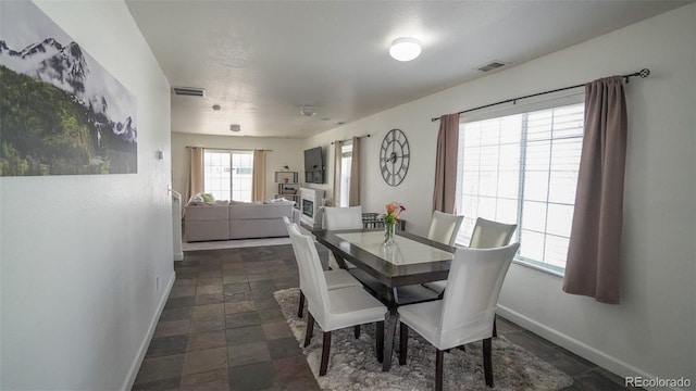 dining room featuring stone finish flooring, baseboards, and visible vents